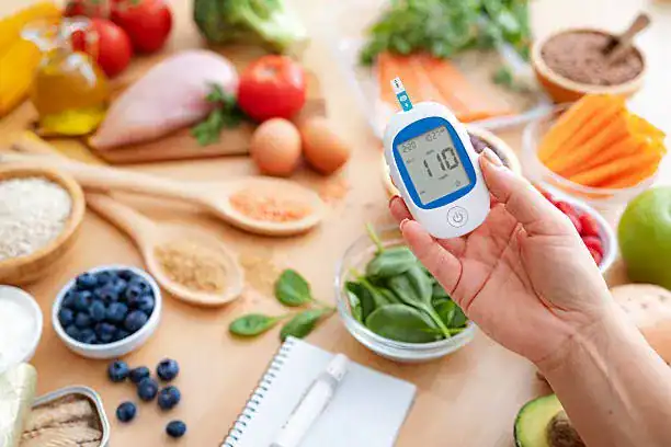 Persona con diabetes midiendo glucosa junto a alimentos sin gluten
